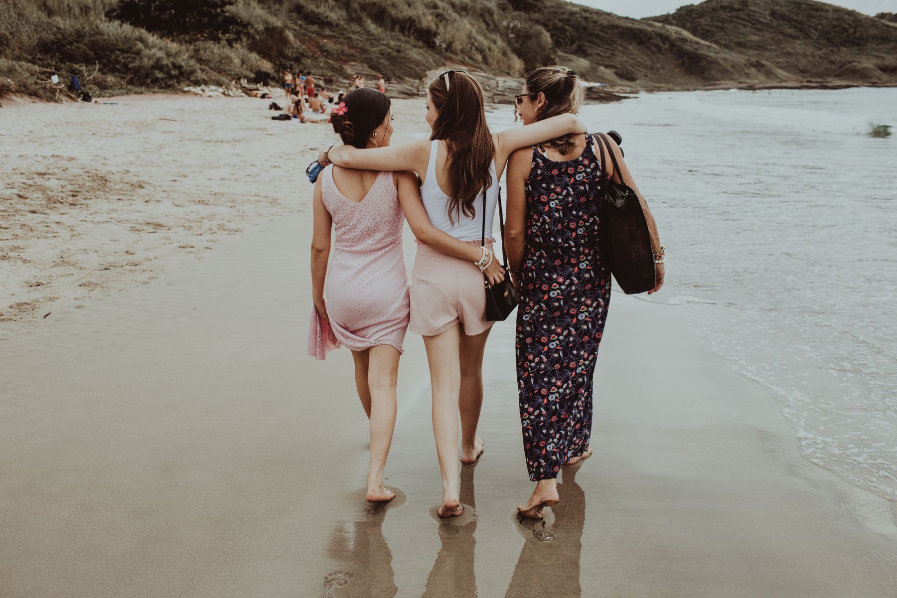 Three women walking together along the shoreline