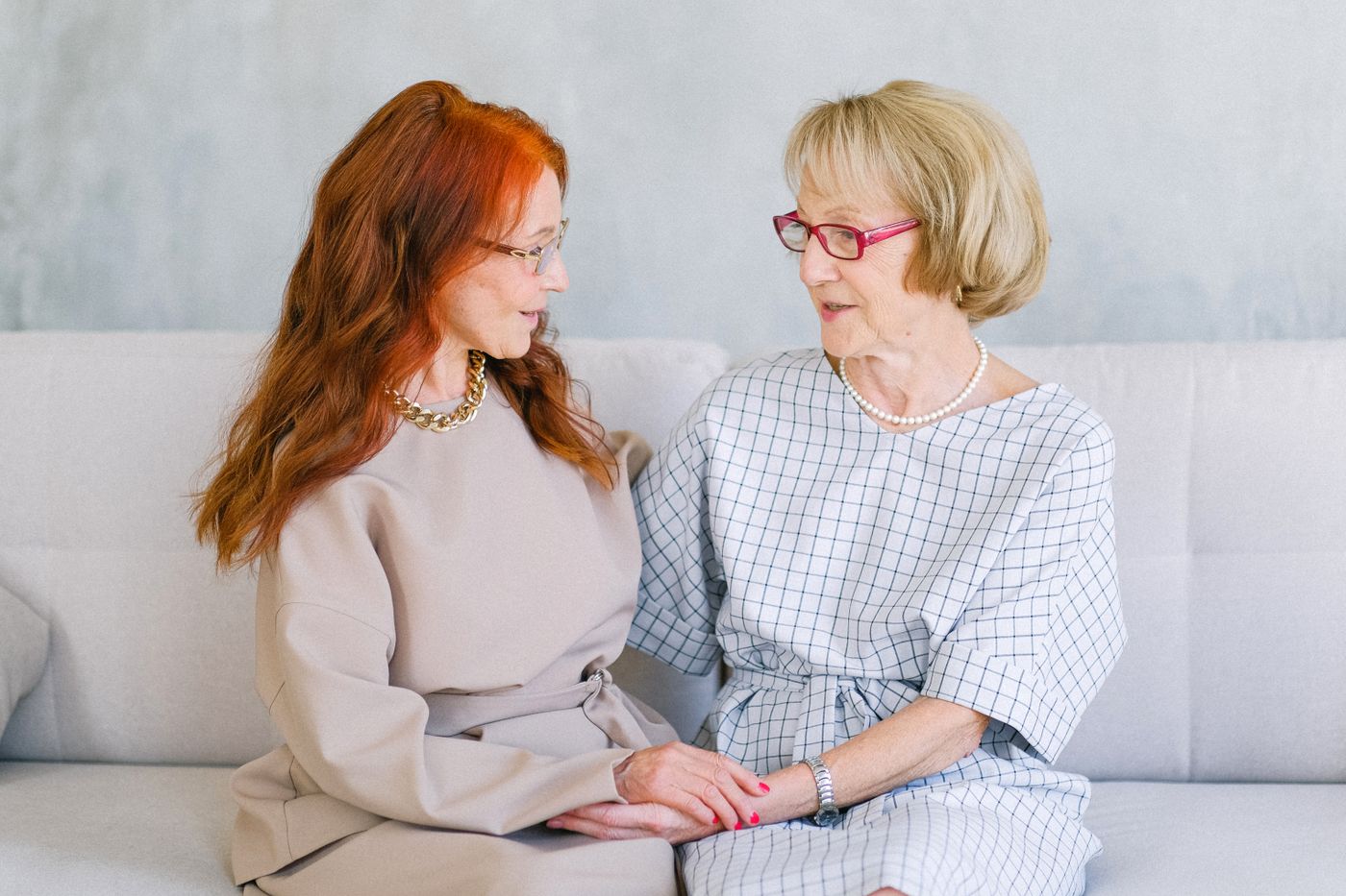 Two older women sitting together and holding hands in conversation